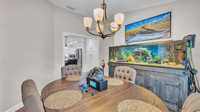 dining room with baseboards, wood finished floors, a chandelier, and visible vents