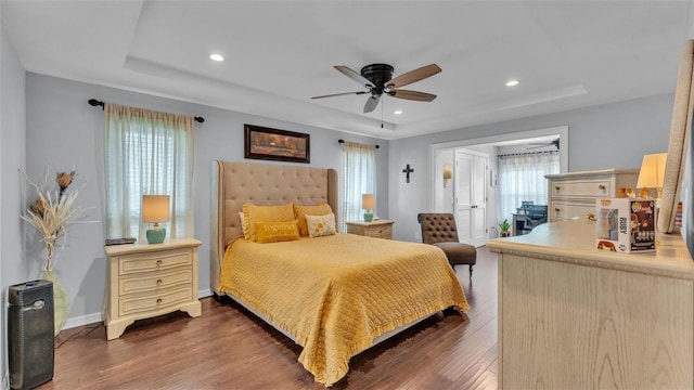 bedroom featuring dark wood finished floors, a tray ceiling, and recessed lighting