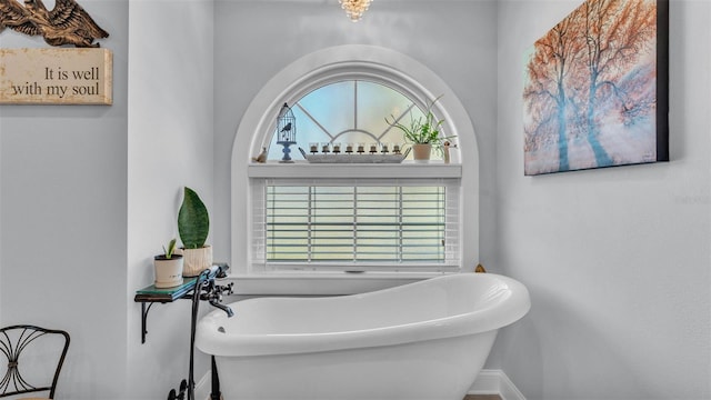full bath with a freestanding bath and baseboards
