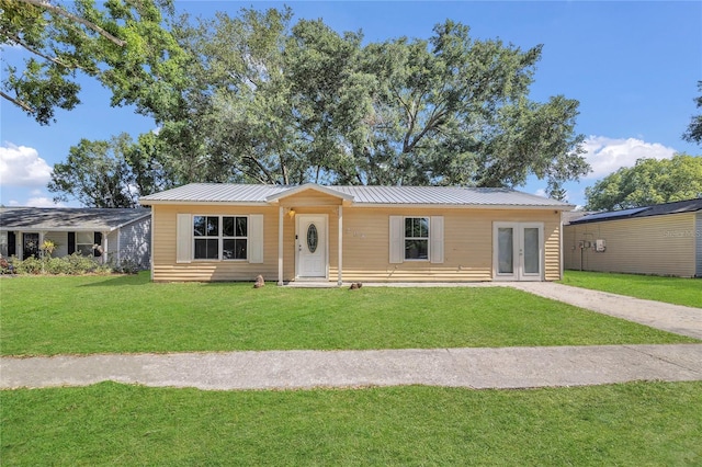 view of front of property with french doors, a front yard, and metal roof
