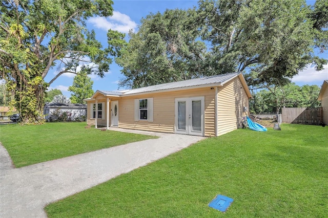 back of house featuring a yard, fence, french doors, and metal roof