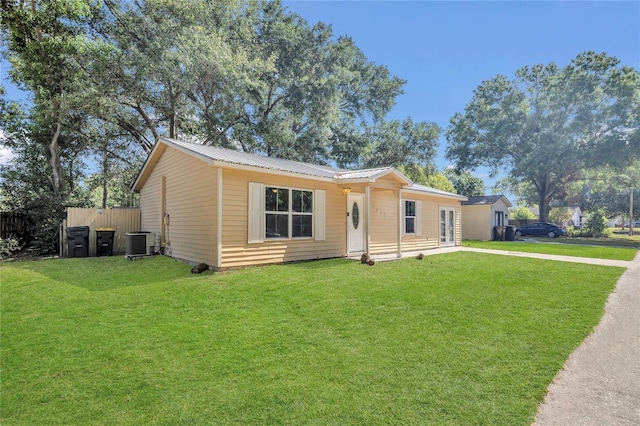 view of front of home featuring central air condition unit, fence, metal roof, and a front yard