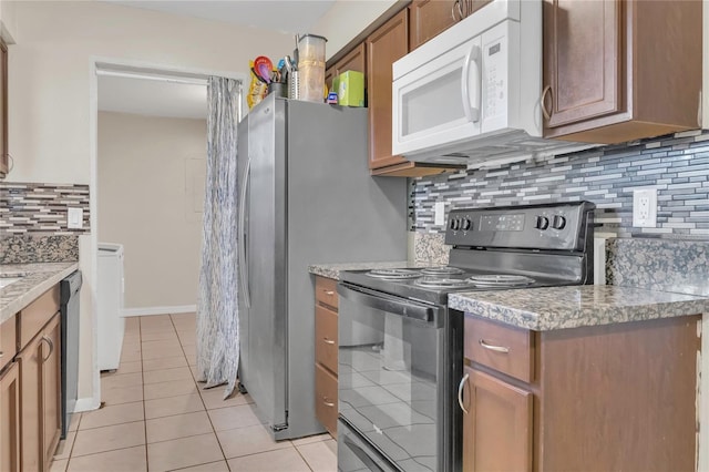 kitchen with light countertops, black electric range oven, light tile patterned floors, white microwave, and backsplash