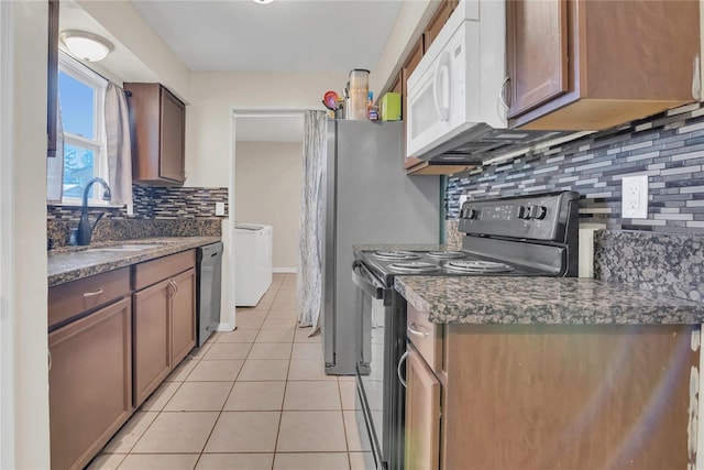 kitchen featuring dark countertops, tasteful backsplash, a sink, light tile patterned floors, and black appliances