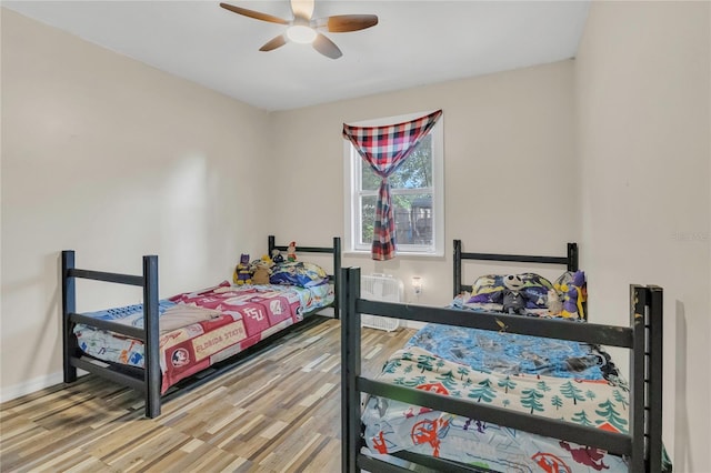 bedroom with a ceiling fan, baseboards, and light wood finished floors