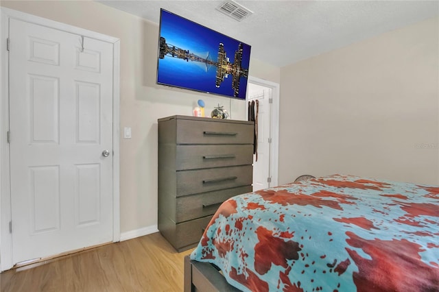 bedroom with visible vents, baseboards, and wood finished floors