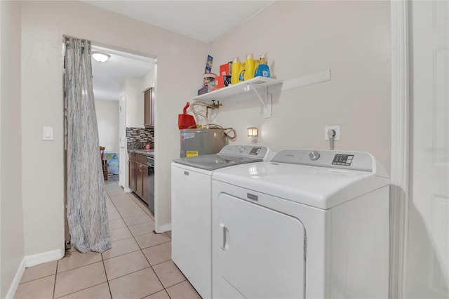 laundry room featuring laundry area, baseboards, light tile patterned floors, washing machine and dryer, and electric water heater