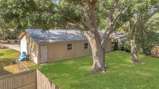 back of house with fence, a yard, and metal roof