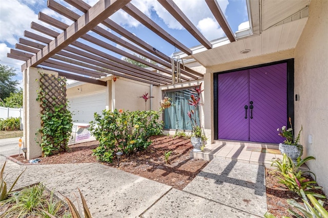 view of exterior entry with a pergola and stucco siding