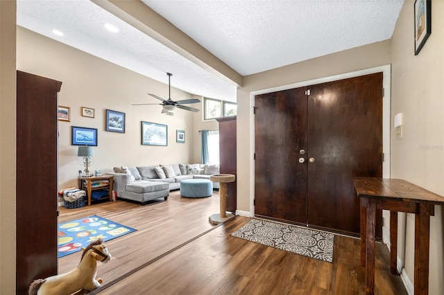 foyer entrance with baseboards, a textured ceiling, ceiling fan, and wood finished floors