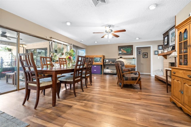 dining room with light wood-style floors, a textured ceiling, a ceiling fan, baseboards, and visible vents