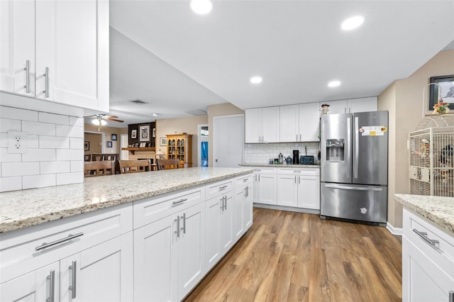 kitchen featuring visible vents, white cabinets, stainless steel fridge with ice dispenser, light wood-style flooring, and backsplash