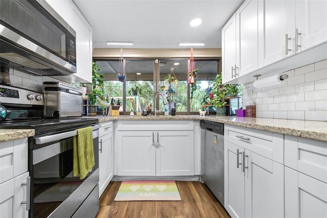 kitchen with white cabinets, appliances with stainless steel finishes, dark wood-style floors, and tasteful backsplash