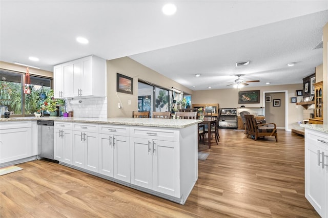 kitchen with a peninsula, ceiling fan, white cabinets, light wood finished floors, and dishwasher