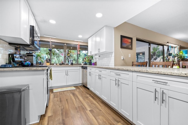 kitchen with tasteful backsplash, white cabinetry, a sink, stainless steel appliances, and light wood-style flooring