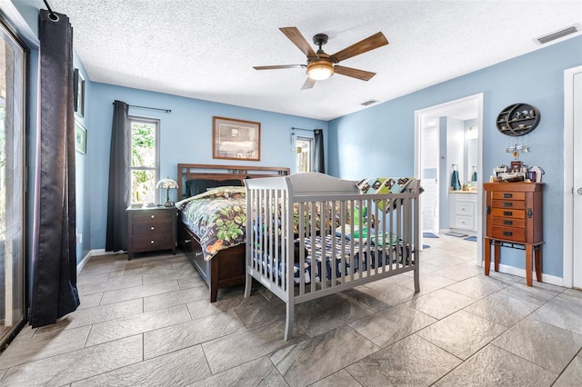 bedroom featuring baseboards, a textured ceiling, and visible vents