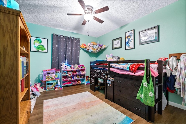 bedroom with a ceiling fan, a textured ceiling, and wood finished floors