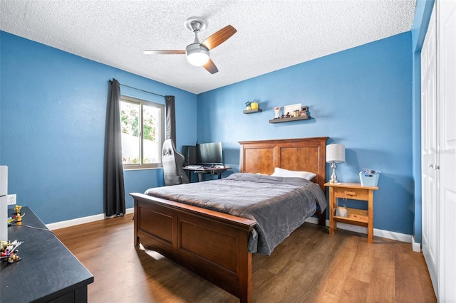 bedroom featuring baseboards, ceiling fan, a textured ceiling, and wood finished floors