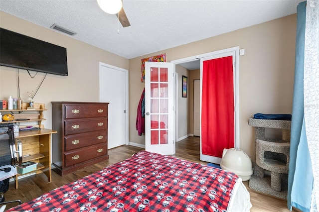 bedroom with visible vents, wood finished floors, ceiling fan, a textured ceiling, and french doors