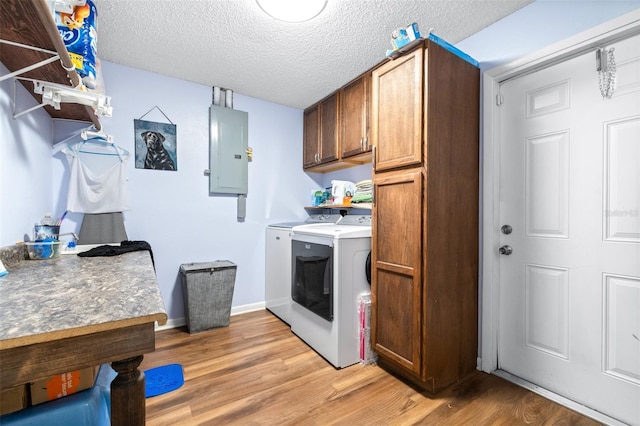 washroom with light wood-style floors, washer and dryer, cabinet space, and electric panel