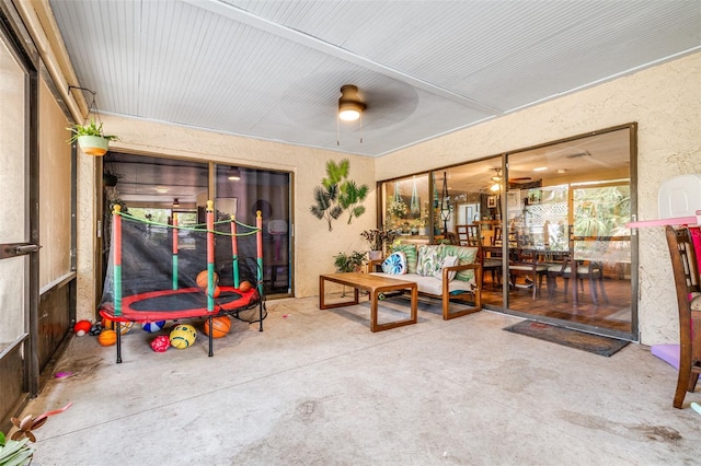 interior space with a ceiling fan, a textured wall, and concrete flooring