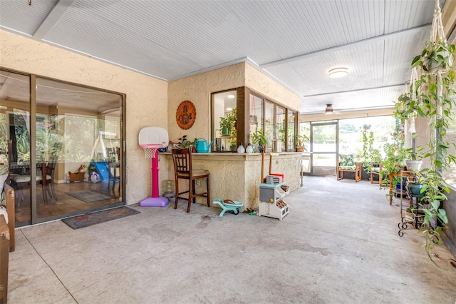 sunroom / solarium featuring a textured wall, concrete floors, and outdoor dry bar