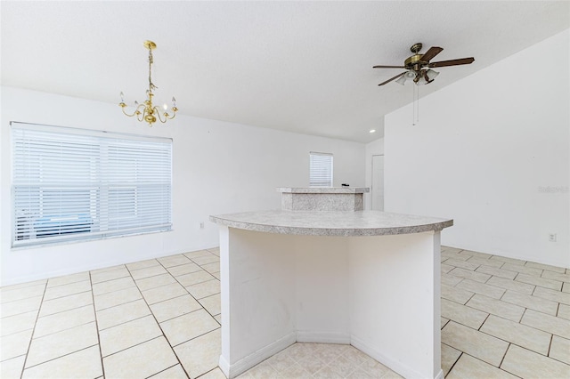 2660 Hemingway Ave, Haines City, FL 33844 - kitchen featuring a center island, light tile patterned floors, hanging light fixtures, ceiling fan with notable chandelier, and light countertops