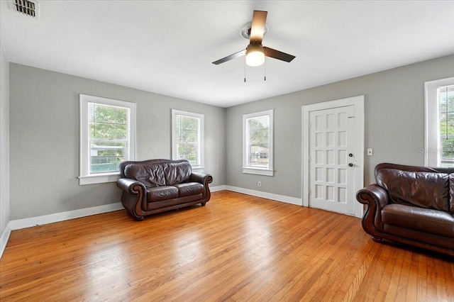 living area with baseboards, visible vents, light wood-style flooring, and a ceiling fan