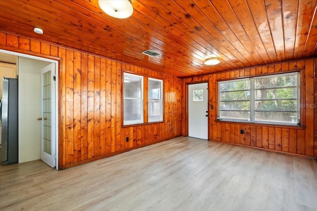 foyer featuring wooden walls, visible vents, light wood-type flooring, and wooden ceiling