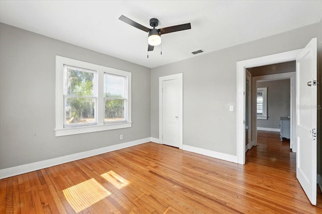 unfurnished bedroom with a closet, light wood-type flooring, visible vents, ceiling fan, and baseboards
