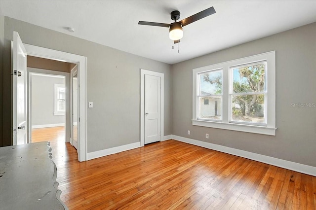 unfurnished bedroom with baseboards, multiple windows, and light wood-style floors
