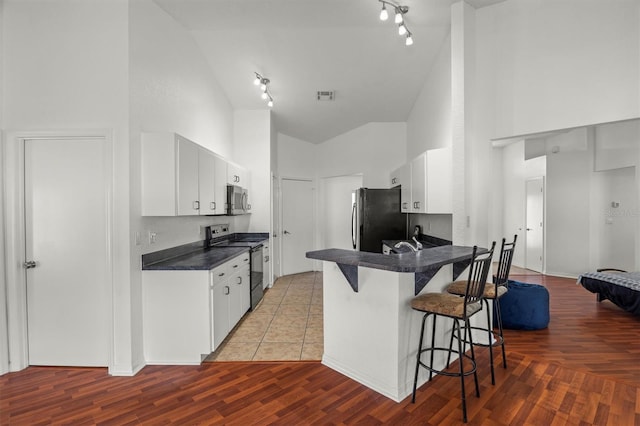 2812 Hickory Ridge Dr, Lakeland, FL 33813 - kitchen with rail lighting, black appliances, high vaulted ceiling, and a kitchen bar