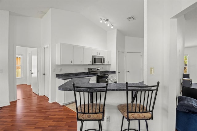 2812 Hickory Ridge Dr, Lakeland, FL 33813 - kitchen with dark countertops, high vaulted ceiling, stainless steel microwave, black range with electric cooktop, and visible vents