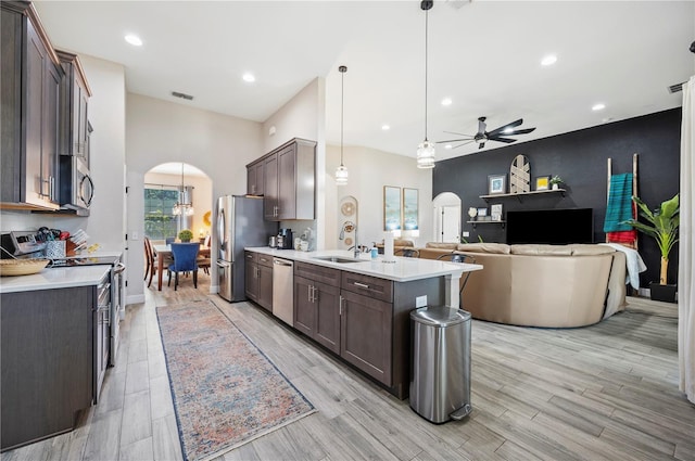 5531 Pebble Beach Dr, Lakeland, FL 33812 - kitchen with arched walkways, dark brown cabinetry, a ceiling fan, and appliances with stainless steel finishes