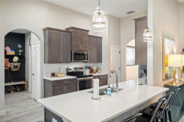 5531 Pebble Beach Dr, Lakeland, FL 33812 - kitchen with a sink, dark brown cabinetry, light wood-style floors, arched walkways, and stainless steel appliances