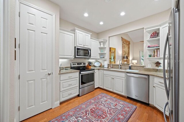 2965 Mission Lakes Dr, Lakeland, FL 33803 - kitchen featuring stainless steel appliances, open shelves, a sink, white cabinetry, and light wood finished floors