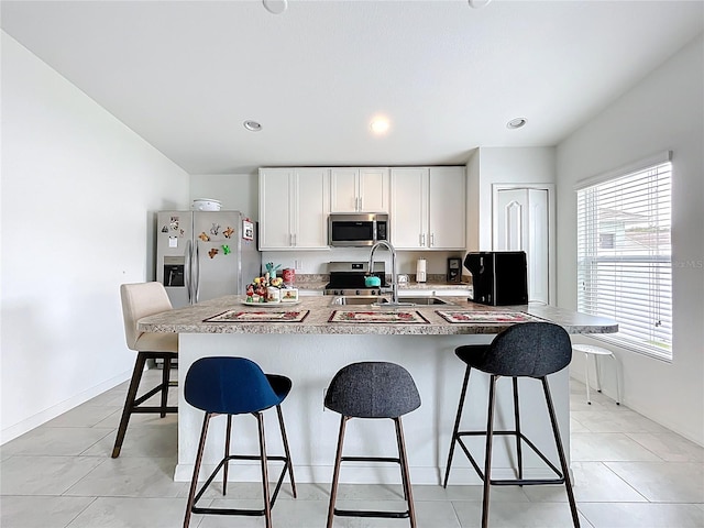 kitchen featuring a breakfast bar, light countertops, white cabinetry, a sink, and stainless steel appliances