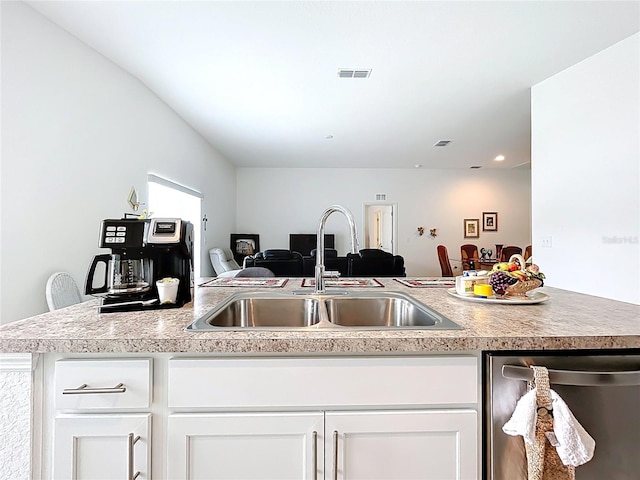kitchen with stainless steel dishwasher, a sink, white cabinets, and light countertops