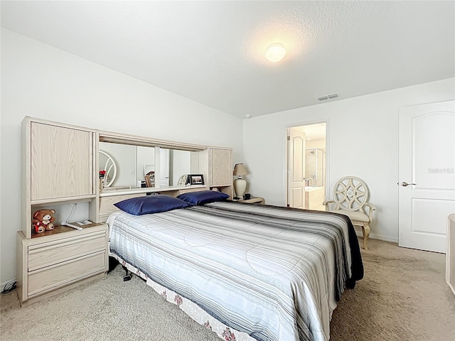 bedroom featuring baseboards, visible vents, light carpet, and ensuite bath