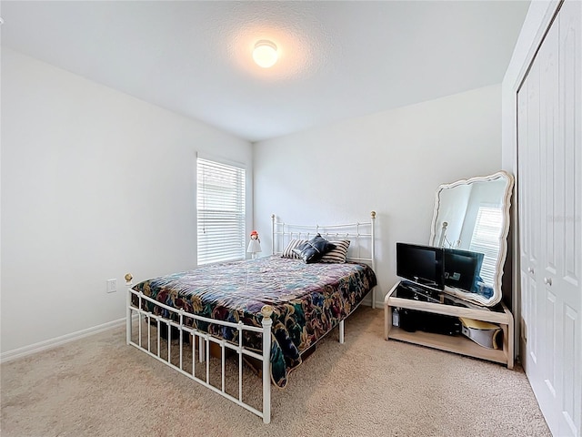 carpeted bedroom featuring baseboards and a closet