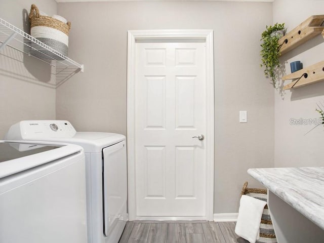 laundry area featuring separate washer and dryer, laundry area, baseboards, and light wood finished floors