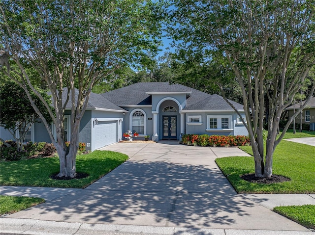 800 Osprey Landing Dr, Lakeland, FL 33813 - view of front of house featuring french doors, an attached garage, stucco siding, a front lawn, and a shingled roof