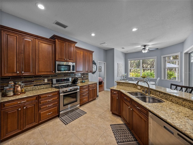 800 Osprey Landing Dr, Lakeland, FL 33813 - kitchen with appliances with stainless steel finishes, a sink, backsplash, a ceiling fan, and light stone counters