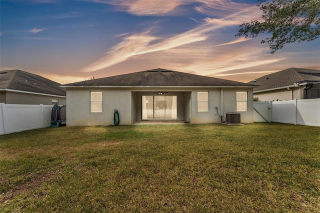 3592 Prescott Loop, Lakeland, FL 33810 - back of house at dusk with a fenced backyard, a gate, stucco siding, and a yard