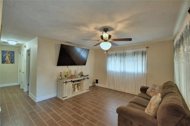 living area with baseboards and ceiling fan