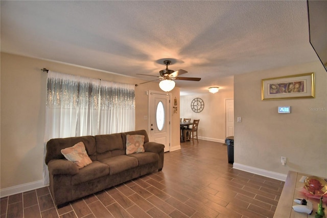 living room with baseboards, a ceiling fan, and dark wood-style flooring
