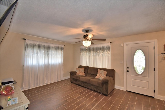 living area with a healthy amount of sunlight, baseboards, and a ceiling fan
