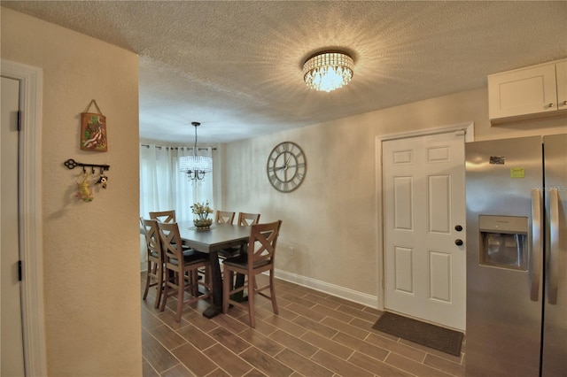 dining space featuring an inviting chandelier, baseboards, a textured wall, and a textured ceiling
