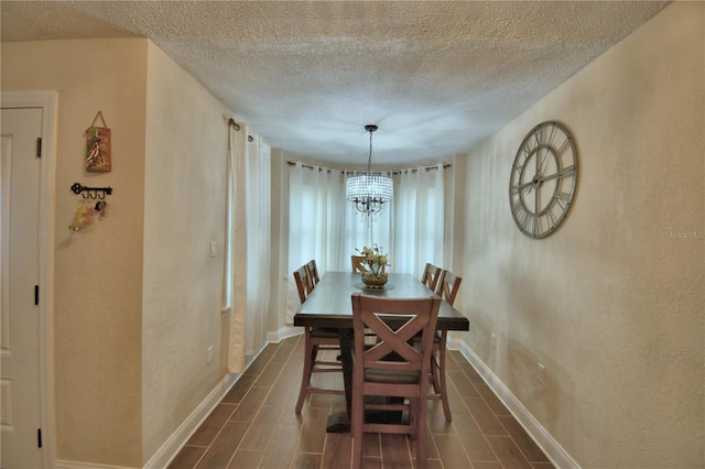 dining space with wood tiled floor, baseboards, a textured ceiling, and a chandelier