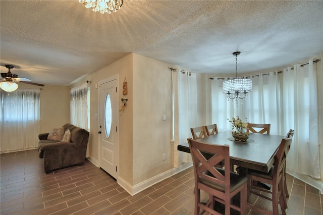 dining room featuring baseboards, ceiling fan with notable chandelier, and a textured ceiling